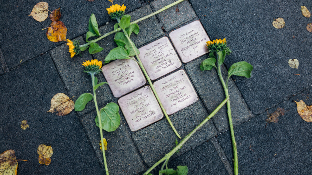 Fünf Stolpersteine, umrahmt von Sonnenblumen.